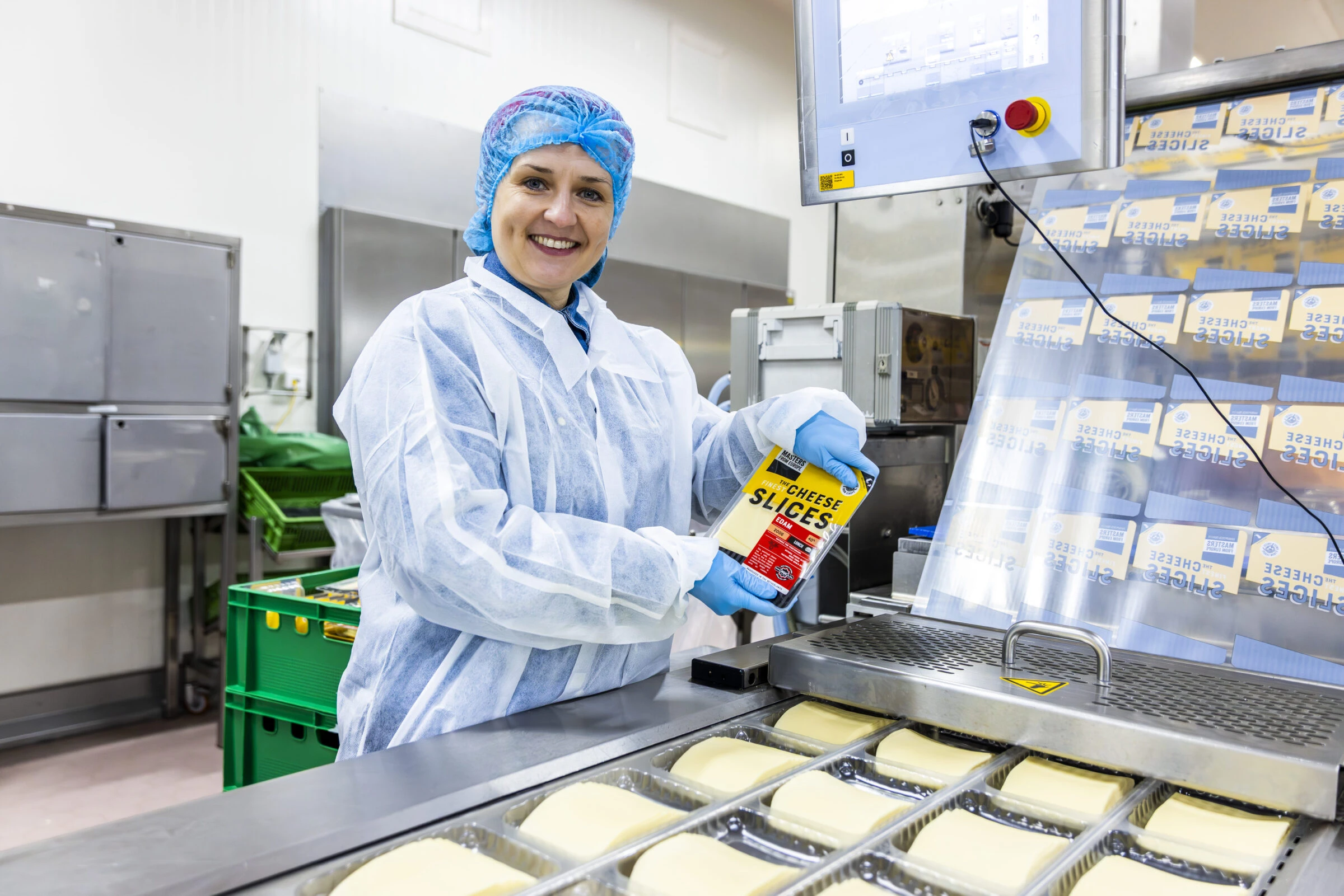 A food production worker in white protective clothing inspecting a Cheese Slices package on the production floor, representing FFT International's strict quality control and food safety standards.